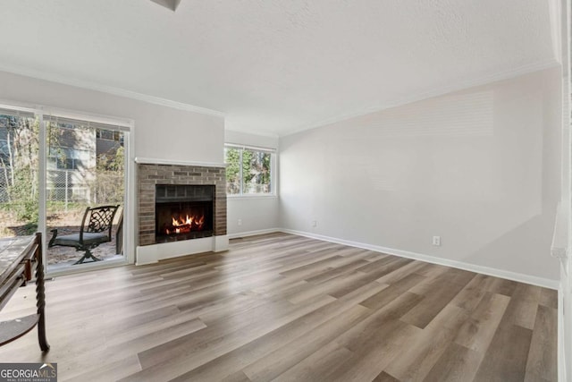 unfurnished living room with a fireplace, ornamental molding, a textured ceiling, and light hardwood / wood-style floors