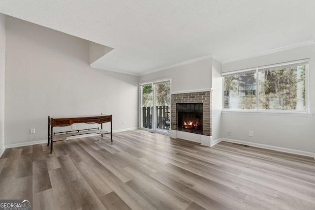 living room featuring a brick fireplace, light wood-type flooring, crown molding, and a textured ceiling