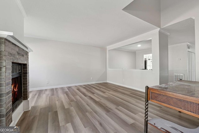 living room with a brick fireplace, light hardwood / wood-style floors, and crown molding