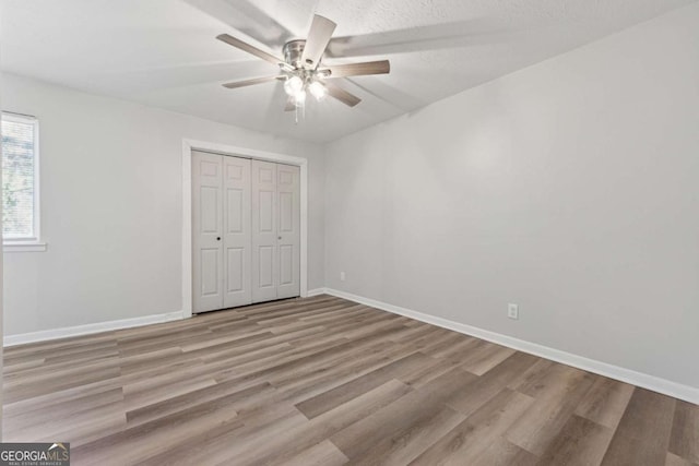 unfurnished bedroom with light wood-type flooring, a closet, and ceiling fan