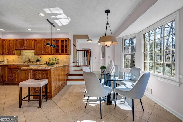 dining area featuring light tile patterned floors, a textured ceiling, visible vents, baseboards, and stairs