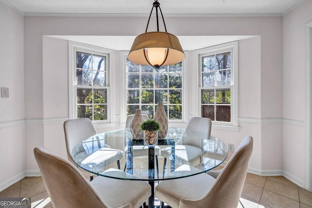 dining space featuring baseboards, crown molding, and light tile patterned flooring