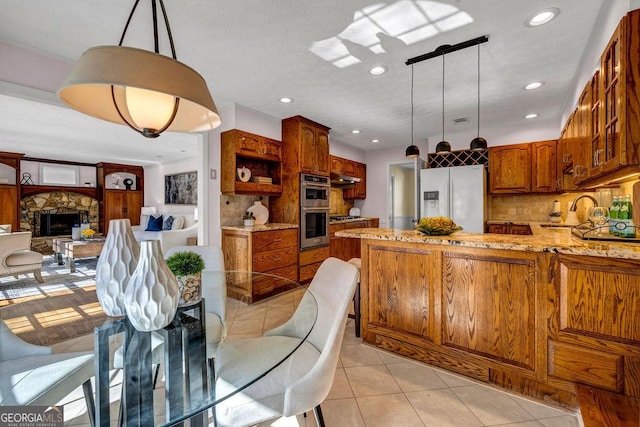 kitchen featuring light tile patterned floors, light stone counters, a peninsula, appliances with stainless steel finishes, and decorative backsplash