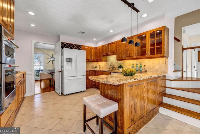 kitchen with a peninsula, light tile patterned floors, white refrigerator with ice dispenser, and decorative backsplash