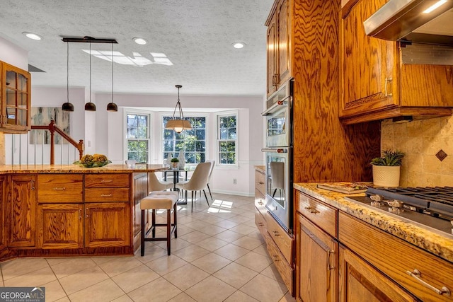 kitchen featuring light tile patterned floors, stainless steel appliances, hanging light fixtures, tasteful backsplash, and brown cabinetry