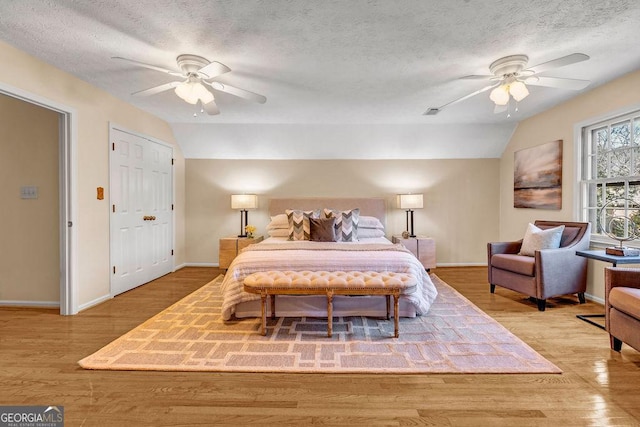 bedroom with a textured ceiling, vaulted ceiling, and wood finished floors