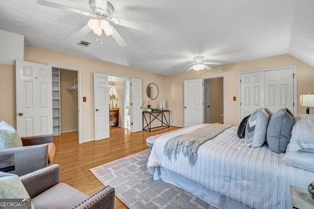 bedroom with a closet, visible vents, a spacious closet, a ceiling fan, and wood finished floors