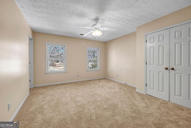 unfurnished bedroom with carpet flooring, visible vents, baseboards, and a textured ceiling