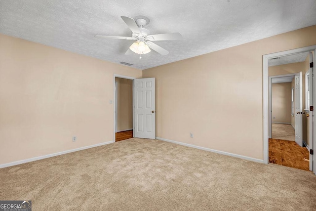 unfurnished bedroom featuring carpet flooring, visible vents, baseboards, and a textured ceiling