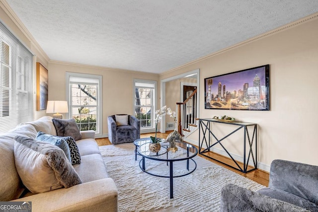 living room with stairway, ornamental molding, a textured ceiling, wood finished floors, and baseboards