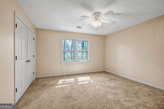 unfurnished bedroom with a textured ceiling, carpet, visible vents, and baseboards