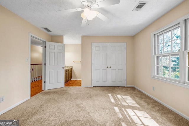 unfurnished bedroom with carpet floors, baseboards, visible vents, and a textured ceiling