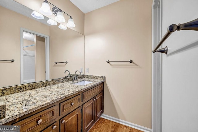 full bathroom with a shower, wood finished floors, vanity, and baseboards