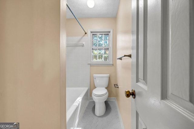 bathroom with baseboards, toilet, tile patterned flooring, a textured ceiling, and shower / washtub combination