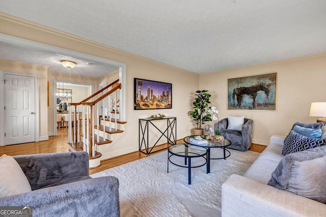 living room with a textured ceiling, wood finished floors, baseboards, ornamental molding, and stairway