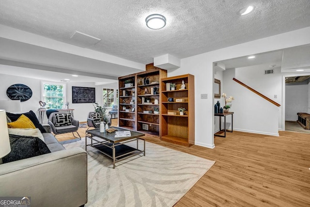 living area featuring visible vents, baseboards, a textured ceiling, light wood-style floors, and recessed lighting