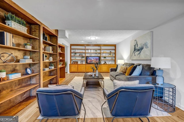 living area with light wood-type flooring and a textured ceiling