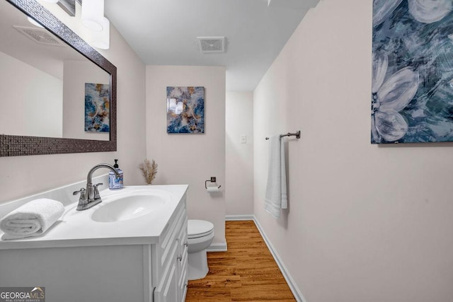 bathroom featuring toilet, visible vents, wood finished floors, and vanity