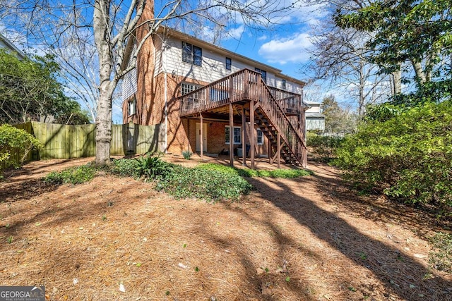 rear view of property with fence, a wooden deck, and stairs