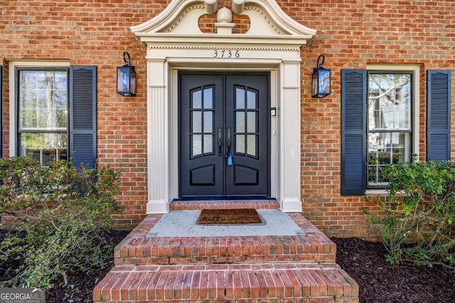 view of exterior entry with brick siding and french doors