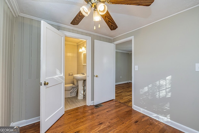 unfurnished bedroom with hardwood / wood-style flooring, ceiling fan, ensuite bathroom, ornamental molding, and sink