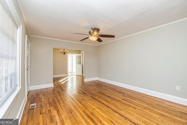 spare room featuring hardwood / wood-style flooring, ornamental molding, and ceiling fan with notable chandelier