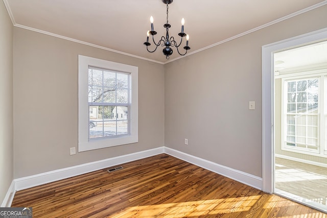 empty room with hardwood / wood-style floors, a notable chandelier, and ornamental molding