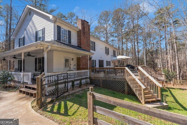 view of front of house featuring ceiling fan, a chimney, stairway, a wooden deck, and a porch