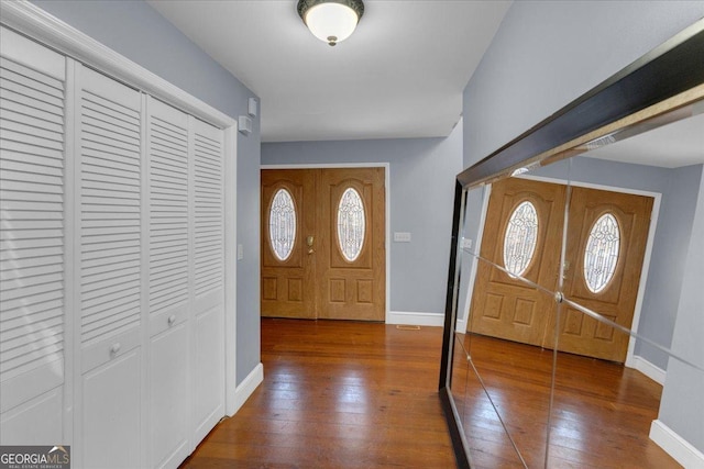 foyer with dark wood-type flooring and baseboards