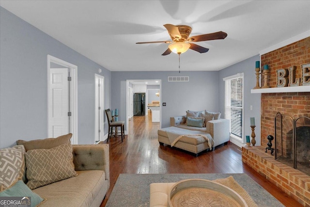 living area with dark wood-style floors, ceiling fan, a fireplace, and visible vents