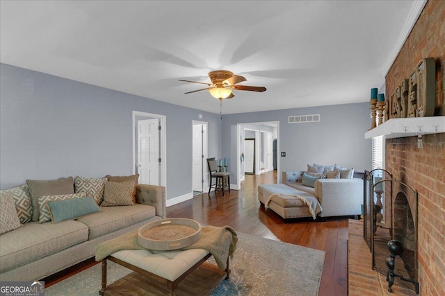 living area with a fireplace, visible vents, a ceiling fan, wood finished floors, and baseboards