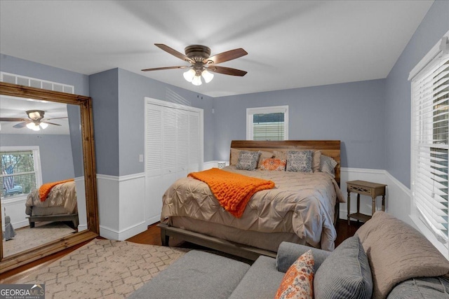 bedroom with ceiling fan, a closet, wood finished floors, and visible vents