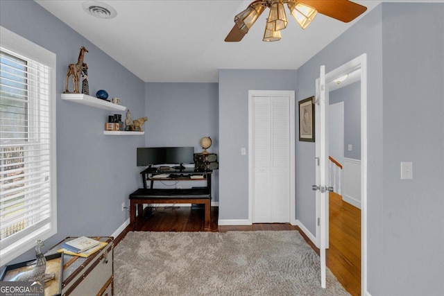 interior space with baseboards, visible vents, multiple windows, and wood finished floors