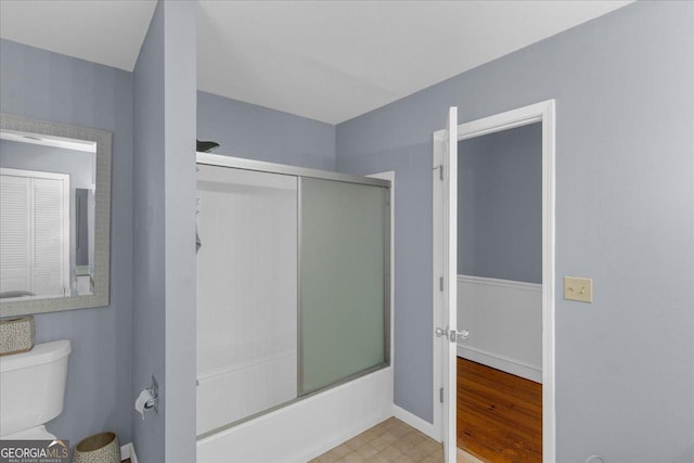 full bath featuring shower / bath combination with glass door, toilet, and tile patterned floors