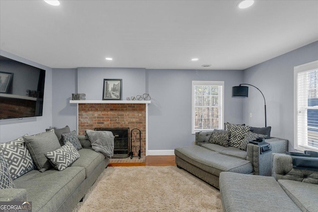 living room featuring light wood-type flooring, plenty of natural light, a fireplace, and recessed lighting