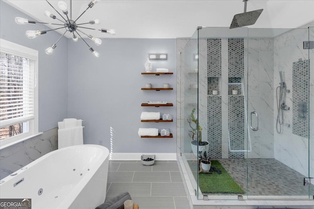 full bathroom with a marble finish shower, an inviting chandelier, tile patterned flooring, a freestanding tub, and baseboards