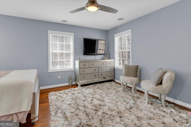 bedroom featuring multiple windows, visible vents, baseboards, and wood finished floors