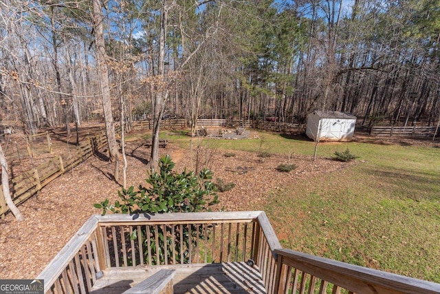 view of yard with an outbuilding, fence, a wooden deck, and a storage unit