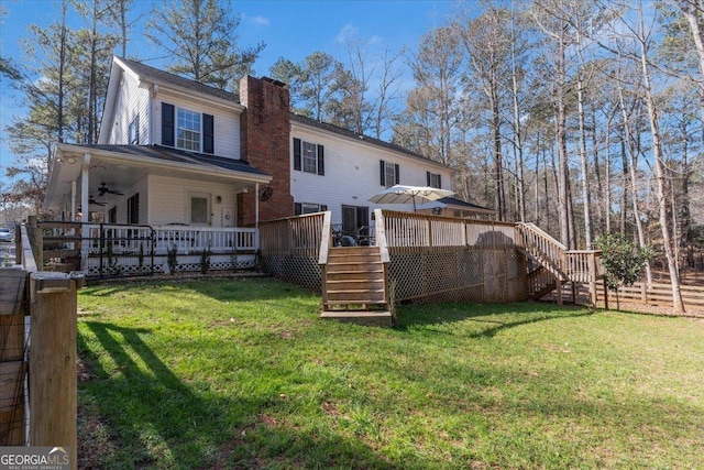 back of house featuring stairs, a chimney, and a lawn