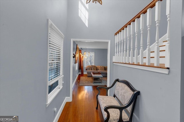 hall with a towering ceiling, stairway, baseboards, and wood finished floors