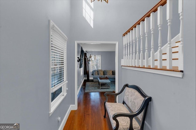 foyer entrance with a towering ceiling, stairs, baseboards, and dark wood-style flooring