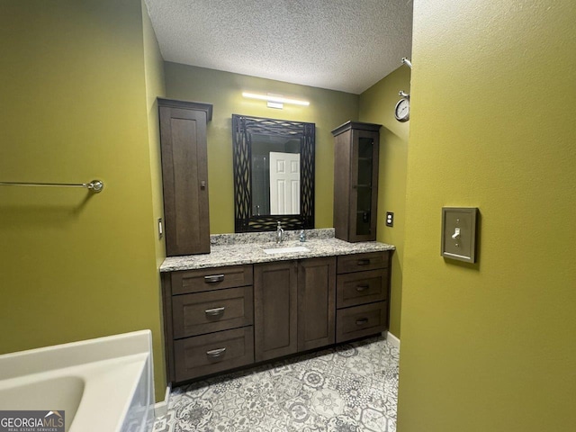 bathroom with vanity, a bathtub, and a textured ceiling