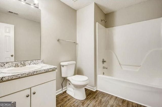 bathroom featuring vanity, wood finished floors, visible vents, tub / shower combination, and toilet