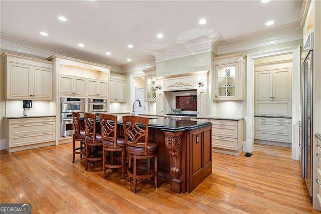 3201 Hobsons Ridge Trl NW, Acworth, GA 30101 - kitchen with stainless steel double oven, ornamental molding, cream cabinets, a center island with sink, and a kitchen breakfast bar