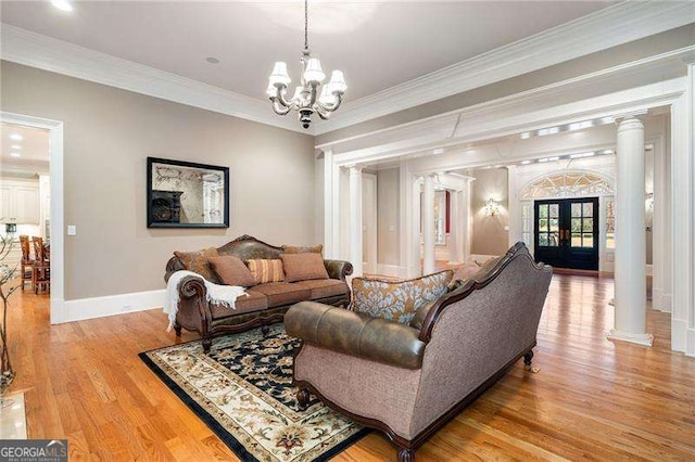 living room featuring light wood-type flooring, french doors, crown molding, and decorative columns