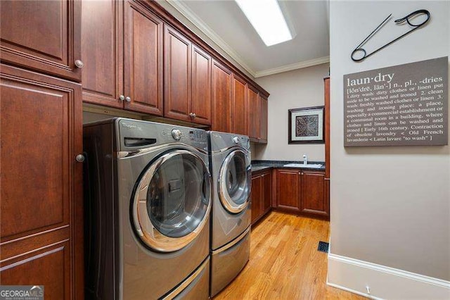 laundry area featuring cabinets, sink, ornamental molding, and washing machine and clothes dryer