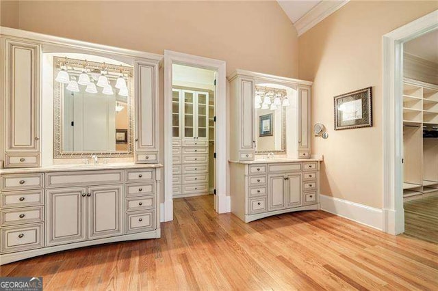 bathroom with lofted ceiling, ornamental molding, vanity, and hardwood / wood-style floors