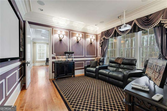 cinema with light wood-type flooring and crown molding