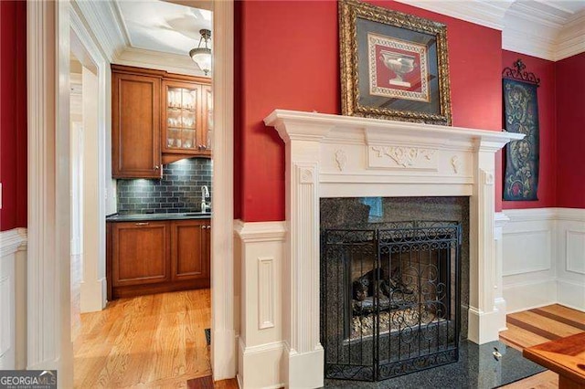 details featuring sink, backsplash, crown molding, and wood-type flooring