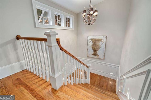 3201 Hobsons Ridge Trl NW, Acworth, GA 30101 - staircase with wood finished floors, a chandelier, and a wainscoted wall